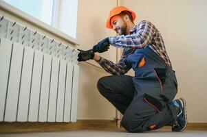 aquecimento sistema instalação e manutenção serviço. encanador instalando radiador foto