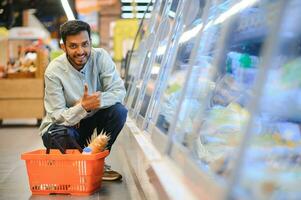 retrato do indiano homem compra dentro uma mercearia loja. comprando mercearia para casa dentro uma supermercado foto