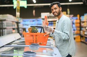 retrato do indiano masculino dentro mercearia com positivo atitude foto