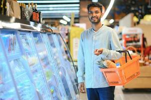 retrato do indiano homem compra dentro uma mercearia loja. comprando mercearia para casa dentro uma supermercado foto