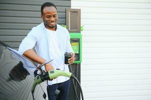 africano americano homem cobrando dele elétrico carro. foto