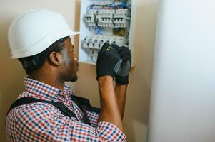 africano americano eletricista reparação eletricidade quadro de distribuição foto