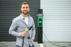 uma homem cobranças a elétrico carro foto