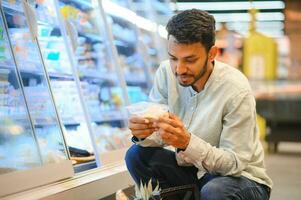 retrato do bonito jovem indiano homem em pé às mercearia fazer compras ou supermercado, fechar-se. seletivo foco. foto