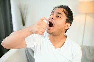 a indiano homem tem a gripe. uma homem usa uma garganta spray. foto