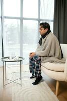 retrato do doente indiano homem com escorrendo nariz segurando papel guardanapos perto face sentado às lar. gripe, vírus, alergia conceito foto