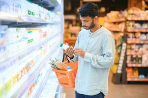 retrato do bonito jovem indiano homem em pé às mercearia fazer compras ou supermercado, fechar-se. seletivo foco. foto