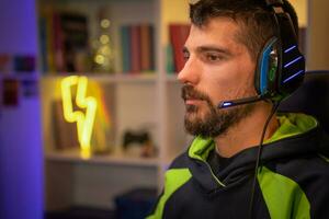 jogador com fones de ouvido jogando profissional conectados vídeo jogos transmissão em computador dentro dele sala. foto