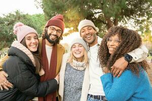 grupo do amigos olhando às Câmera sorridente ao ar livre dentro uma parque dentro inverno. foto