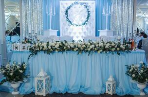 a Casamento mesa do a noiva e noivo, decorado com flores, é fez dentro azul e prata. velas em fica. branco flores e vegetação. prata. Casamento detalhes foto