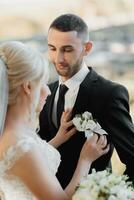 a noiva vestidos a noivo dentro uma flor na lapela do branco rosas em a Casamento dia foto