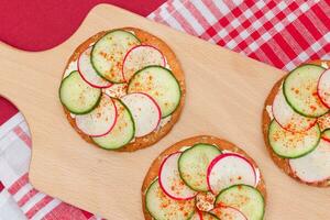 luz café da manhã ou dieta comendo - crocantes biscoito sanduíche com creme queijo, fresco pepino e rabanete em de madeira cozinhando borda em magenta fundo foto