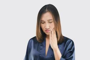 uma mulher dentro uma Sombrio azul cetim roupão tem uma dor de dente. foto