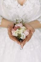 Casamento detalhes. a noiva detém a do noivo Casamento flor na lapela. mãos guardada dentro a forma do uma coração. lindo mãos. francês manicure foto