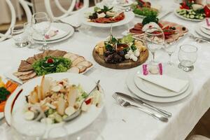 bufê mesa às uma casamento. queijo placa. sortimento do canapés. banquete serviço. comida, lanches com queijo, presunto, prosciutto e fruta. César salada. vidro óculos. prata mesa conjuntos. foto