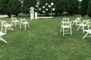 Casamento cerimônia dentro a jardim. uma luxuoso Casamento cerimônia. romântico Casamento cerimônia. a carrinhos estão decorado com colorida flores branco cadeiras foto