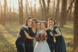 noiva com damas de honra em a parque em a Casamento dia. damas de honra dentro azul vestidos e noiva segurando lindo buquês. lindo luxo Casamento blog conceito. verão casamento. foto