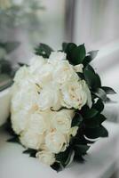uma ramalhete do branco rosas e vegetação em uma branco fundo. uma lindo foto com detalhes do a casamento. Casamento dia. luz do dia.