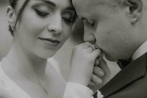 a noivo Beijos a da noiva mão, Preto e branco foto, à moda noivas. delicado inventar. Casamento anel foto