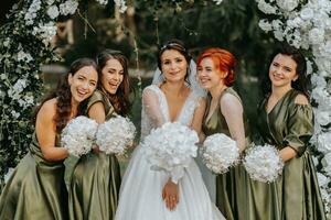 damas de honra sorridente juntos com a noiva. a noiva e dela Diversão amigos comemoro a Casamento depois de a cerimônia dentro Coincidindo vestidos. noiva e amigos dentro natureza foto