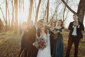 noivas e amigos dentro a natureza. amigos às a casamento. recém-casado casal, damas de honra e padrinhos tendo Diversão ao ar livre foto