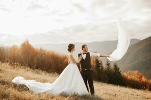 feliz Casamento casal posando sobre uma lindo montanha panorama. Casamento véu dentro a ar foto