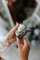 a concurso mão do a noiva detém a flor na lapela para a noivo. a noiva é segurando uma flor na lapela. mãos guardada dentro a forma do uma coração. francês manicure. Casamento detalhes foto