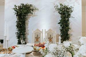 Casamento mesa servindo. Casamento luxo decoração. Casamento presídio para a recém-casados. lindo decoração com pastel rosas, velas e vegetação. dentro de casa foto