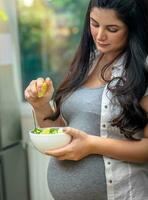 grávida mulher comendo uma salada foto