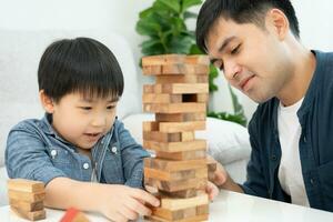 Ásia feliz solteiro pai jogando Aprendendo jogos janga com a pequeno garoto. engraçado família é feliz e animado dentro a casa. pai e filho tendo Diversão gastos Tempo junto. feriado, fim de semana, vago. foto