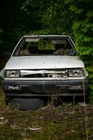 velho dilapidado carro dentro uma floresta foto