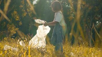 criança menina coleção plástico lixo dentro natureza. criança colheita acima Lixo dentro parque. foto