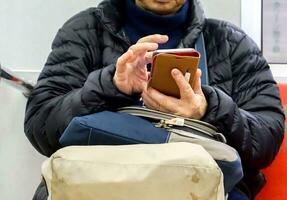 fechar-se e colheita humano dentro inverno terno toque e apreciar jogando Internet em Móvel telefone enquanto esperando para a trem. foto