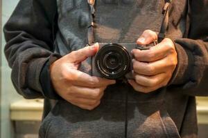 fechar-se mãos do turista homem segurando uma moderno Câmera com forma do sombra e brilhante claro. foto