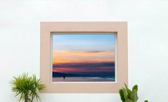 branco parede concreto textura com aberto janela quadro, Armação olhando Fora para mar Visão com pôr do sol s dentro a de praia areia, exterior branco cimento casa, mínimo moderno construção com tarde céu e casa plantas foto