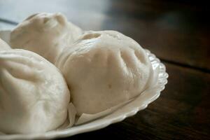 fechar-se e colheita chinês quente pão em branco cerâmico prato e de madeira mesa fundo. chinês quente pão estão vários tipos popular dentro inverno dentro China, hong kong, Taiwan. foto