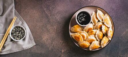crocantes frito dumplings com soja molho e sésamo sementes em uma prato topo Visão rede bandeira foto