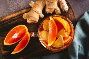 fechar acima do perfumado chá com peças do laranja e gengibre dentro uma copo em a mesa topo Visão foto