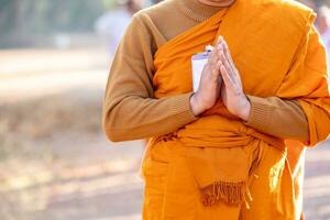 budista monge é em pé com dele mãos guardada dentro a forma do uma lótus para executar alguns religioso ritual, uniforme budista monge, budista monge Rezar foto