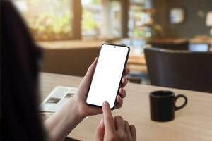 manhã café cena. mulher segurando Smartphone com isolado tela para aplicativo apresentação, acompanhado de uma jornal em a mesa. perfeito para exibindo tecnologia e lendo hábitos foto