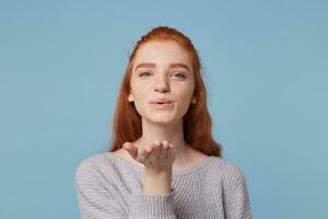 fofa adorável alegre aberto tipo ruivo menina golpes uma beijo às a Câmera isolado contra uma azul fundo foto