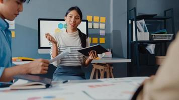 jovens empresários e mulheres de negócios asiáticos felizes reunindo-se e debatendo algumas novas idéias sobre o projeto para seu parceiro, trabalhando juntos, planejando uma estratégia de sucesso, desfrute do trabalho em equipe em um pequeno e moderno escritório em casa. foto