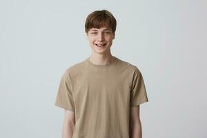 fechar-se do alegre loiro bonito jovem homem com saudável dentes e metal suspensórios desgasta bege t camisa sente feliz isolado sobre branco fundo parece diretamente dentro Câmera foto