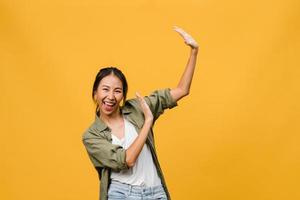 retrato de jovem asiática com expressão positiva, sorriso amplo, vestido com roupas casuais sobre fundo amarelo. feliz adorável feliz mulher alegra sucesso. conceito de expressão facial. foto