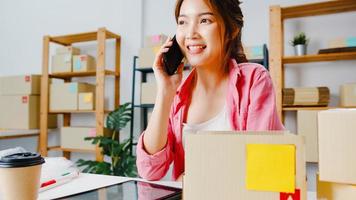 jovem empresária da ásia usando telefone celular para receber o pedido de compra e verificar o produto em estoque, trabalhar no escritório em casa. proprietário de uma pequena empresa, entrega de mercado online, conceito freelance de estilo de vida. foto