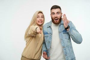 espantado jovem bonita casal levantando emocionalmente seus mãos enquanto olhando surpreendentemente às Câmera com Largo olhos aberto, em pé sobre branco fundo foto