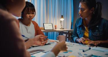 close-up asiáticos empresários reunindo plano de análise estatísticas brainstorm e cabeçalho da equipe seguram tablet gráfico gráfico ponto e funcionário tomam nota na noite do escritório em casa. conceito de sucesso de estratégia de finanças.
