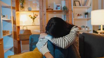 senhora asiática pensativa, sofrendo de insônia, sente-se no sofá na sala de estar à noite em casa com a sensação de solidão, adolescente deprimido e triste, passar um tempo sozinho ficar em casa, distância social, quarentena de coronavírus. foto