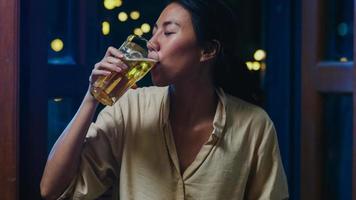 jovem asiática bebendo cerveja se divertindo feliz noite festa ano novo evento on-line celebração via videochamada por telefone em casa à noite. distância social, quarentena para coronavírus. ponto de vista ou pov