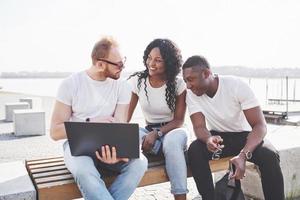 lindos amigos multi-étnicos usando um laptop na rua. conceito de estilo de vida jovem foto